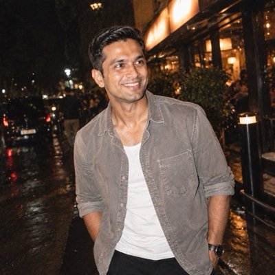 ChatGPT result: a man in a washed-grey shirt on a wet street at night, lit by flash